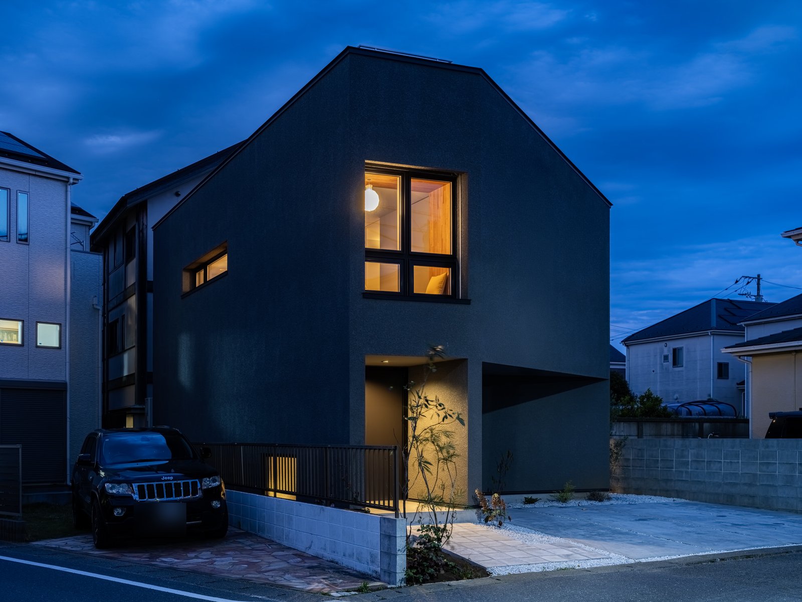 夜、窓に灯りがともる住まいの外観